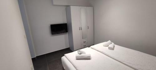 a white room with two beds and a television at Zoran Apartments in Sveti Stefan
