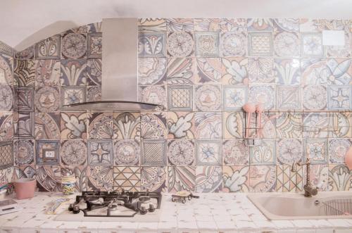 a kitchen with a tile wall with a stove and a tub at Chibedda Dimora Lia in Acitrezza