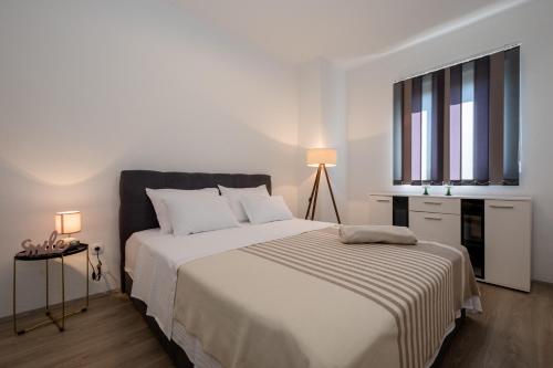 a white bedroom with a large bed and a window at Apartments Sole in Rab