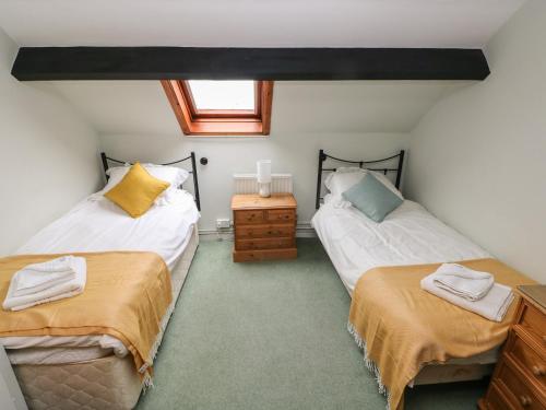 two twin beds in a room with a window at Barn Cottage in Spittal