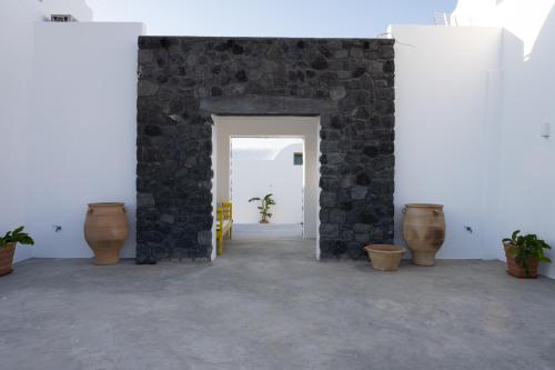 a room with a stone wall and some vases at Oia Kissiri - Private Pool Villas in Oia