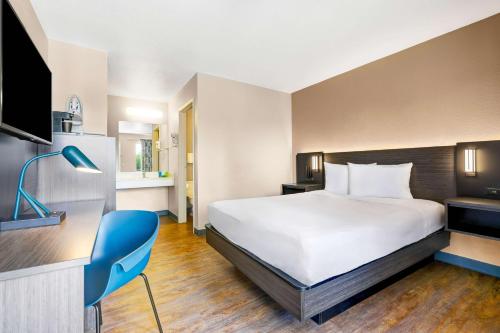 a hotel room with a large bed and a blue chair at Motel 6-Kirkland, WA - North Kirkland in Kirkland