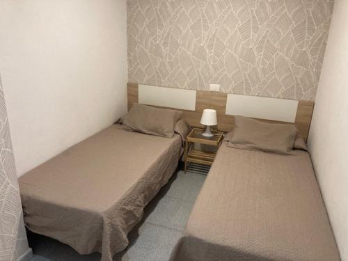 2 camas en una habitación pequeña con una lámpara en una mesa en Vacacional Playa Las Canteras, en Las Palmas de Gran Canaria