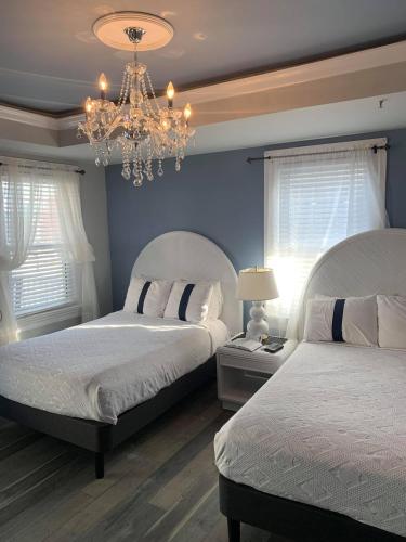 a bedroom with two beds and a chandelier at Ocean Manor 1100 Inn in Ocean City