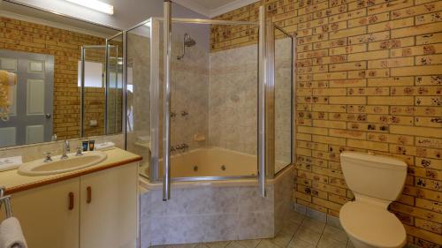 a bathroom with a shower and a toilet and a sink at Mulga Country Motor Inn in Charleville