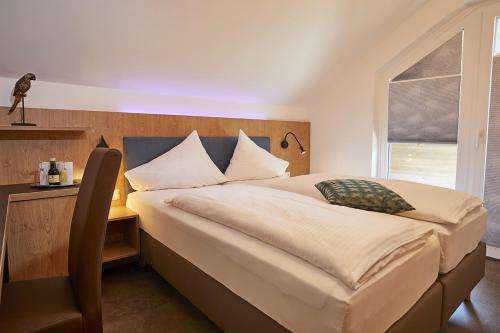 a bedroom with a large bed with a desk and a window at Dei Hotel Schönblick in Velden am Wörthersee