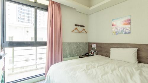 a bedroom with a bed and a large window at 台中逢甲九九商旅 in Taichung
