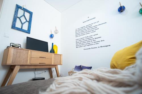 a bedroom with a bed and a desk with a television at Feel Nazaré - Boutique Apartments in Nazaré