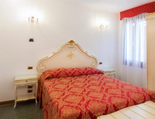 a bedroom with a bed with a red bedspread at Hotel Leonardo in Venice