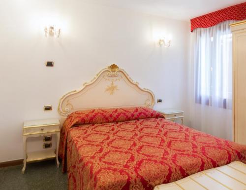 a bedroom with a bed with a red bedspread at Hotel Leonardo in Venice