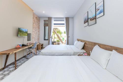 a hotel room with two beds and a desk at Tran Long Cu Hin Hotel - Near Bai Dai Beach in Cam Lâm