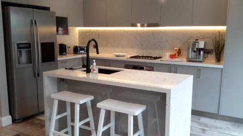 a kitchen with a counter with stools and a refrigerator at Camden Valley Terrace 4 