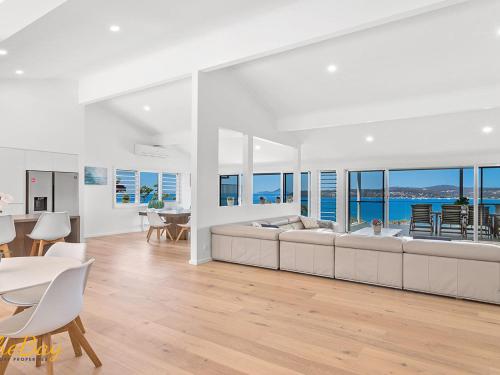 sala de estar con sofá grande, mesa y sillas en Randall Drive No 64, en Salamander Bay