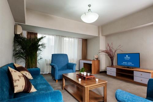 a living room with a blue couch and a tv at Hotel Nikko Apartment Dalian in Dalian