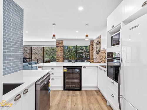 a kitchen with white countertops and appliances and windows at Bay Parklands Unit 70 in Nelson Bay