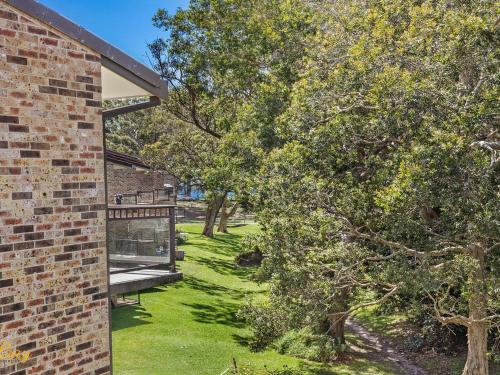 a brick building with a bench in a yard at Bay Parklands Unit 70 in Nelson Bay