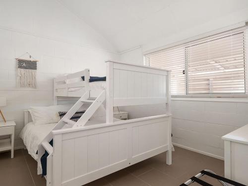 a white bedroom with a white bunk bed and a window at Little Kingsley Beach House in Boat Harbour