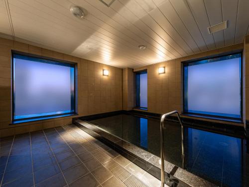 a swimming pool with two large windows in a building at Granbell Hotel Osaka in Osaka