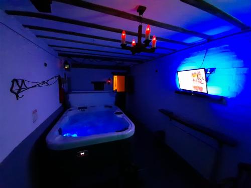 a dark room with a tub and a tv at Stable cottage cozy,quirky with a hot tub in Bridlington