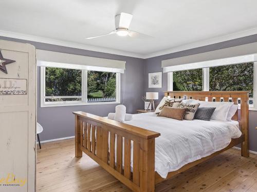 ein Schlafzimmer mit einem großen Bett und zwei Fenstern in der Unterkunft Morton Cottage at Lemon Tree in Lemon Tree Passage