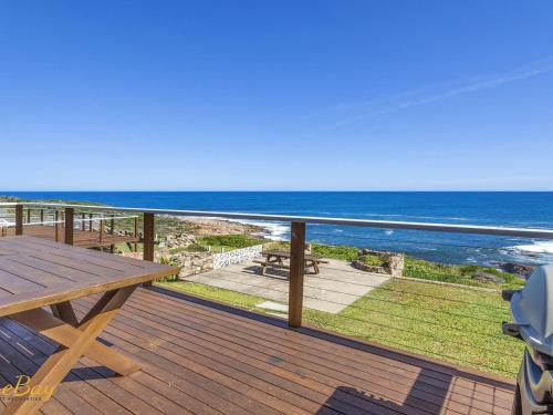 a wooden deck with a picnic table and the ocean at Elanora Ocean St No 8 in Anna Bay