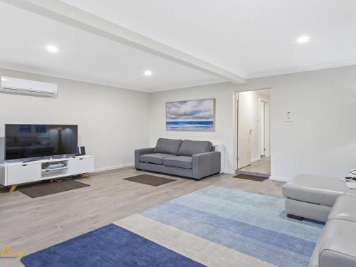 a living room with a couch and a flat screen tv at Twilight on Sunset Beach Soldiers Point in Soldiers Point