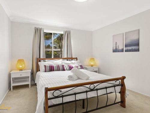 a white bedroom with a bed and two night stands at Blue Fish 41 Boulder Bay Road in Fingal Bay