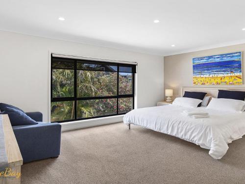 a bedroom with a large bed and a large window at Beach House 72A Marine Dr Fingal Bay in Fingal Bay