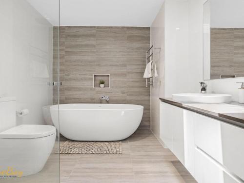 a white bathroom with a tub and two sinks at Beach House 72A Marine Dr Fingal Bay in Fingal Bay