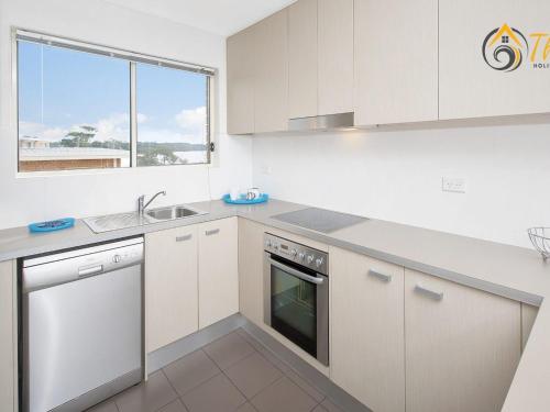 a kitchen with white cabinets and a sink and a window at Shoal Towers No 9 in Shoal Bay