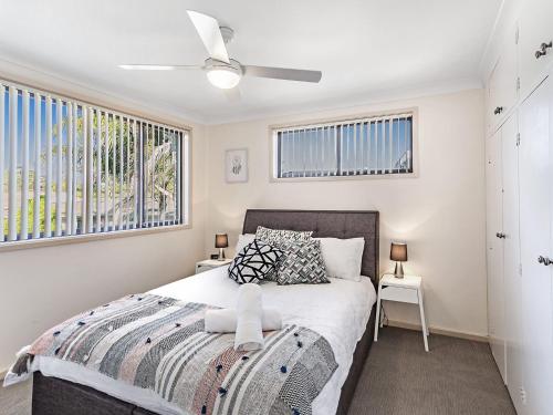 a bedroom with a bed and two windows at Karinya at Little Beach Upstairs in Nelson Bay