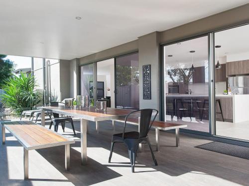 a dining room with tables and chairs and a kitchen at Forever Fingal 205 Rocky Point in Fingal Bay