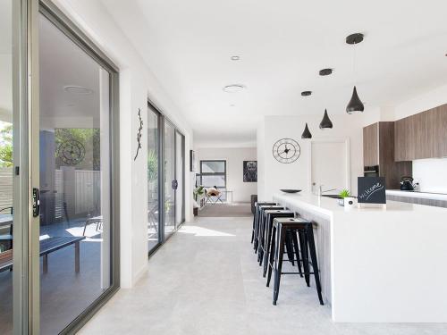 a kitchen with a white counter and stools at Forever Fingal 205 Rocky Point in Fingal Bay