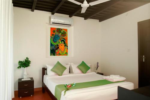 a bedroom with two beds and a painting on the wall at Mayas Beach House in Mararikulam