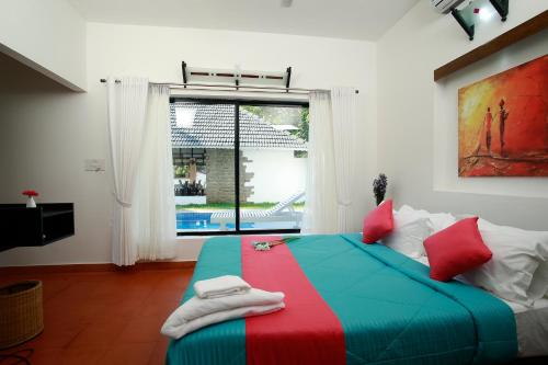 a colorful bed in a room with a window at Mayas Beach House in Mararikulam