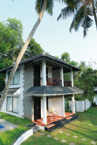 a house with a balcony and two palm trees at Mayas Beach House in Mararikulam