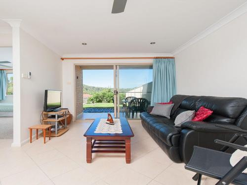 a living room with a black leather couch and a table at Matador Flat Pet Friendly Accommodation in Nelson Bay