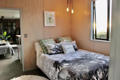 a bedroom with a bed in a room with a window at The Beach House on the Hill in Raglan