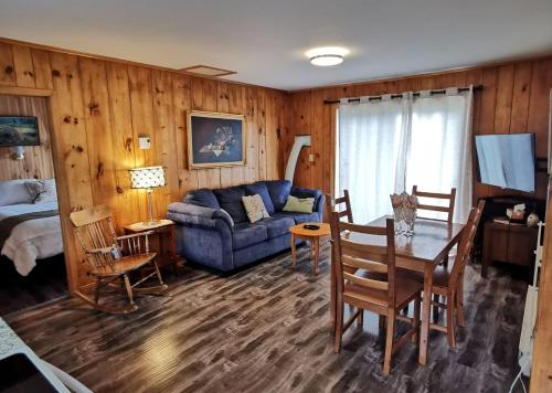 uma sala de estar com um sofá e uma mesa em Knotty Pine Cottages, Suites & Motel Rooms em Ingonish Beach