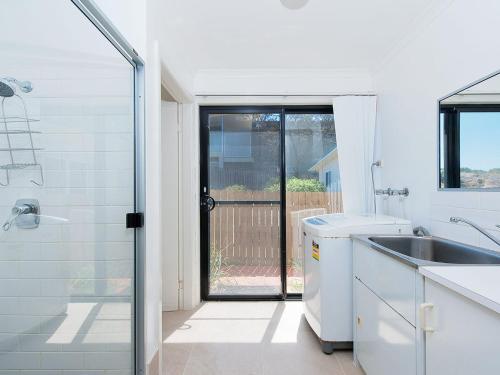 a white bathroom with a sink and a shower at Birubi Point Anna Bay 17A in Anna Bay