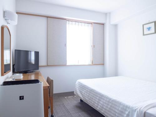 a hotel room with a bed and a television at Hotel Belleview Nagasaki Dejima in Nagasaki