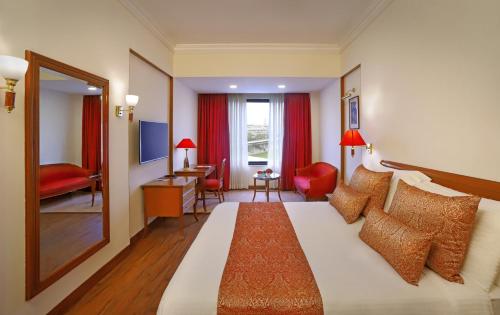a hotel room with a large bed and a mirror at The Ambassador, Marine Drive, Mumbai in Mumbai