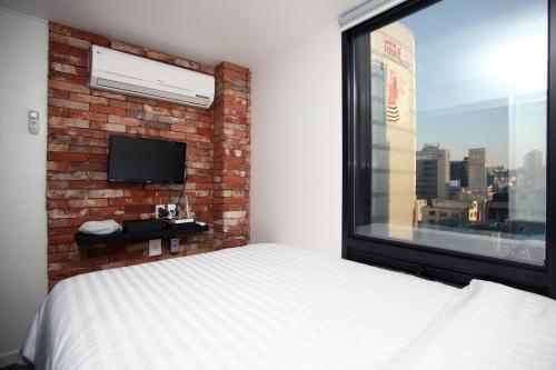a bedroom with a brick wall and a bed and a window at KSTAR METRO Hotel in Seoul