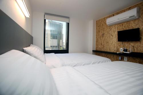 a hotel room with three beds and a window at KSTAR METRO Hotel in Seoul