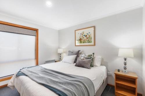 a white bedroom with a bed and a window at City Four Apartment in Mount Gambier