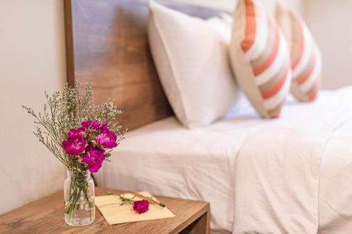 a vase of flowers on a table next to a bed at Tran Long Cu Hin Hotel - Near Bai Dai Beach in Cam Lâm