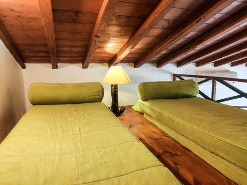 two green beds in a room with wooden ceilings at VILLA VICTORIA in Ditropo