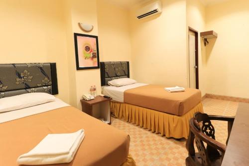 een hotelkamer met 2 bedden en een tafel bij Al-Badar Hotel Syariah Makassar in Makassar