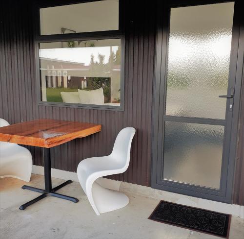 a table and two white chairs and a window at Last Light Lodge in Tuatapere