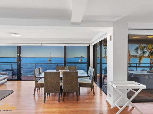 a dining room with a table and chairs and the ocean at Wanda Beach Unit 2 Soldiers Point Road in Salamander Bay